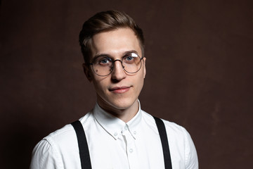 Man in round glasses, suspenders and a white shirt.