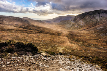 Beautiful valley with river in Mourn Mountains at autumn colours. Dramatic cloudy sky. Highest and most dramatic mountain range in Northern Ireland.
