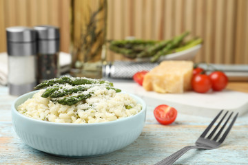 Delicious risotto with asparagus and cheese on wooden table. Space for text