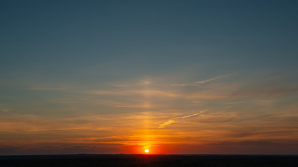 Setting sun on a background of blue sky with clouds.