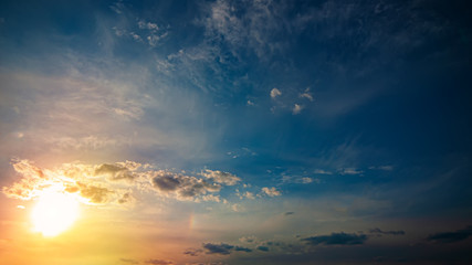 setting sun and rays against the blue sky with clouds.