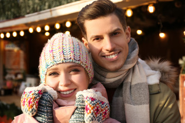 Obraz premium Happy couple in warm clothes at winter fair. Christmas season