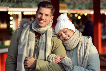 Fototapeta na wymiar Happy couple in warm clothes at winter fair. Christmas season