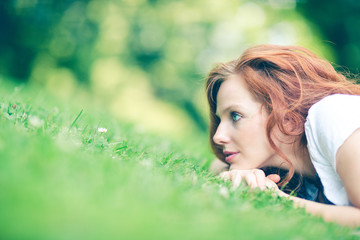 Naklejka na ściany i meble portrait of young red haired woman lying on the grass