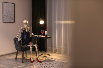 Skeleton in dress with wine sitting at table indoors - Powered by Adobe