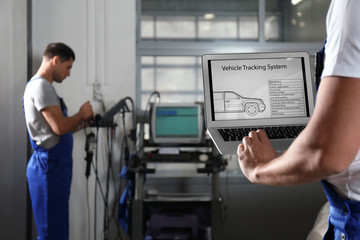 Fototapeta premium Mechanic with laptop doing car diagnostic at automobile repair shop, closeup. Space for text