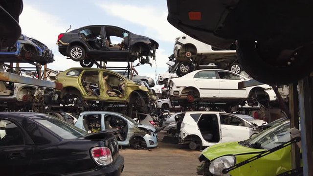 Large Salvage Car parts and Vehicles lot, with rows of stacked totalled Cars.