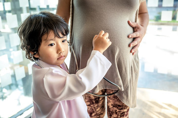Photo of kid doctor and stethoscope with pregnant mother in the office