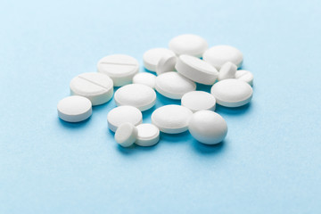 scattered white pills on a blue table. Layout for special offers such as advertising or other ideas. The concept of medicine, pharmacy and healthcare. Space for copy. flat lay for text or logo.