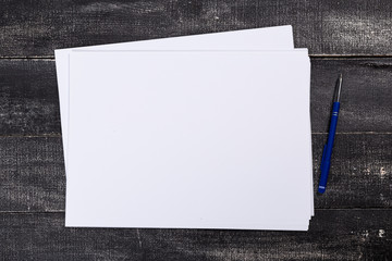 A4 white paper with pen on wooden background. Blank branding template. Photo blank form. Layout for portfolio design.