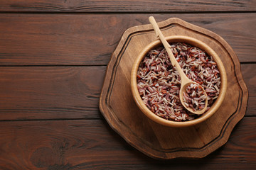 Delicious brown rice served on wooden table, top view. Space for text