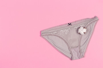 Female pastel cotton set panties and cotton flower on pink background top view flat lay with copy...