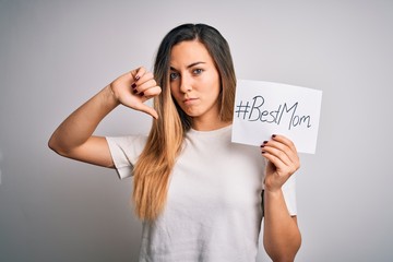 Young beautiful woman holding paper with best mom message celebrating mothers day with angry face, negative sign showing dislike with thumbs down, rejection concept