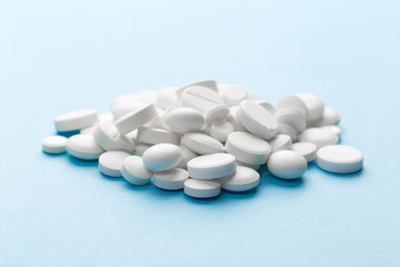 scattered white pills on a blue table. Layout for special offers such as advertising or other ideas. The concept of medicine, pharmacy and healthcare. Space for copy. flat lay for text or logo.