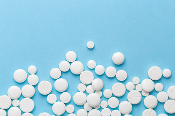 scattered white pills on a blue table. Layout for special offers such as advertising or other ideas. The concept of medicine, pharmacy and healthcare. Space for copy. flat lay for text or logo.