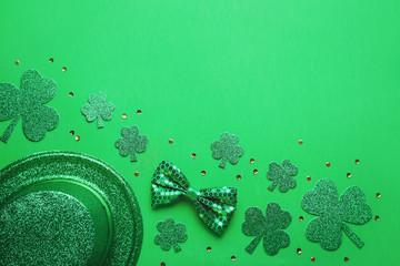 Happy Saint Patrick's Day greeting card with traditional symbols, shamrock, green attire. Green hat, bow tie, St Patricks Day shamrocks, golden confetti on green background, copy space