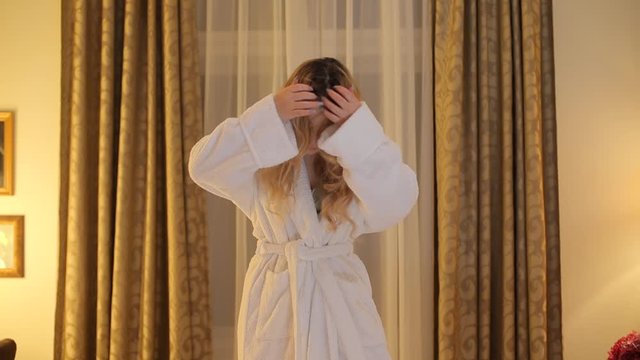 A girl in a bathrobe at a photoshoot poses for the photographer