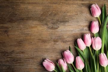Beautiful pink spring tulips on wooden background, flat lay. Space for text