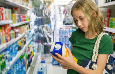 Little girl choosing orange juice in supermarket.