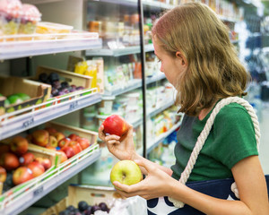 Pretty little girl choosing apples in the supermarket.