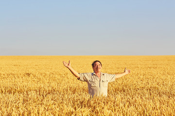Satisfied mature farmer touching with care his ripe wheat field