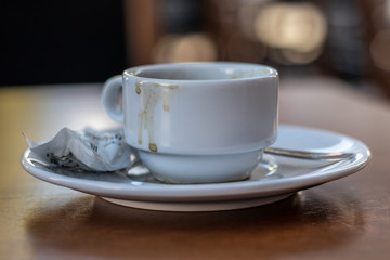 Dirty cup of coffee on a wooden table with bokeh background