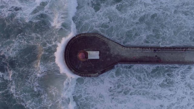 Aerial view of people walking on pier amidst splashing waves in the sea, Porto, Portugal