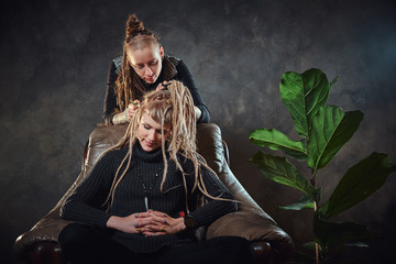 Process of dreadlocks making - female master is working on girl's hair.