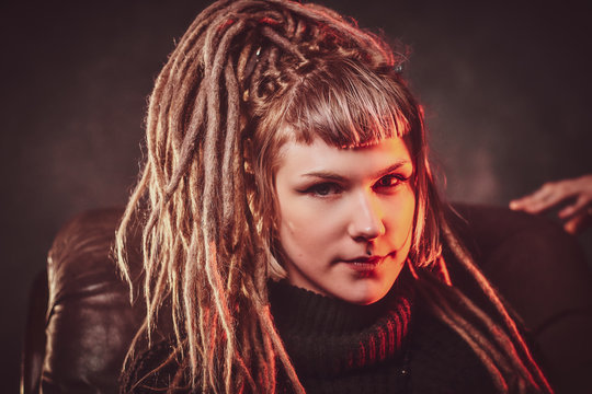 Portrait of young pretty woman with dreadlocks over dark background.