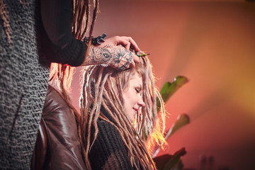 Process of dreadlocks making in the hair studio, blond girl receives a good service.