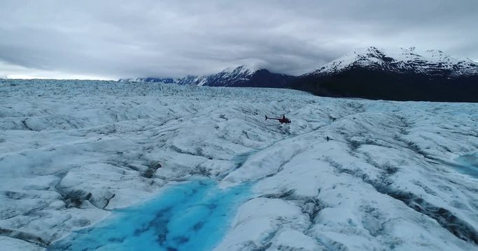 Drone footage of helicopter landing while man running on frozen landscape, Alaska, USA