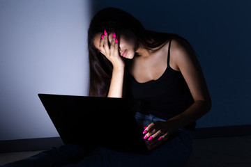 sad and female teenager with tablet computer and laptop suffering cyberbullying and harassment...