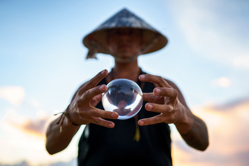 Young guy magician holding a glass ball for contact juggling at sunset