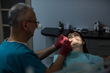 Fototapeta premium Young female patient with senior male dentist having a dental treatment.