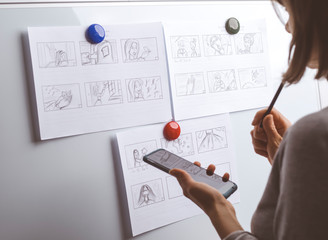Woman draws a storyboard for an animated film on a white board. 