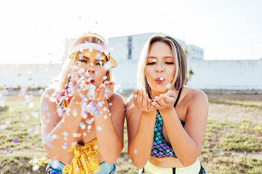 Brazilian Carnival. Young women dressed for the carnival block enjoying the party blowing confetti