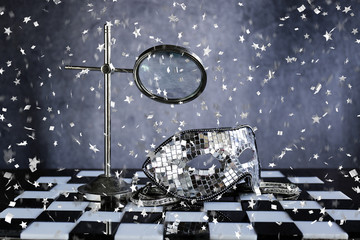 Maschera d'argento sopra la scacchiera bianca e nera ,la festa dei coriandoli e cristalli