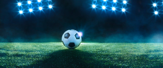 Soccer ball on a sports field backlit by spots