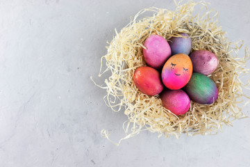 On a gray concrete background, chicken eggs are painted in different colors. Happy Easter theme.