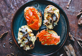 Italian bruschetta with salmon, eggs, cheese and mushrooms in a plate delicious food 