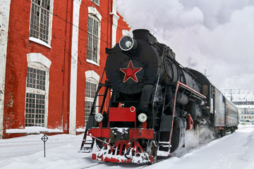 steam locomotive passing through train station in winter