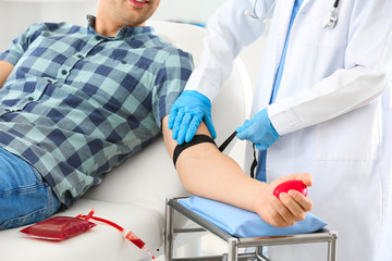 Female doctor preparing male donor for blood transfusion in hospital