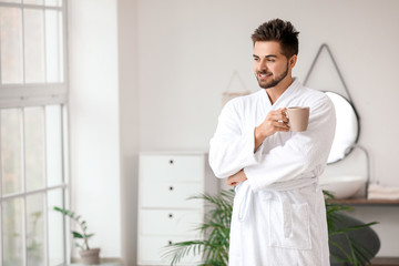 Fototapeta premium Handsome young man drinking tea in bathroom