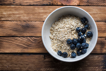 Oatmeal with blueberries in a bowl on a wood background