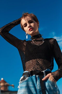 Urban Style. Young stylish woman in choker standing hand in pocket outdoors posing tuching head posing bottom view