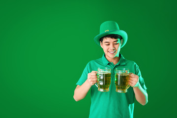 Young Asian man with beer on color background. St. Patrick's Day celebration