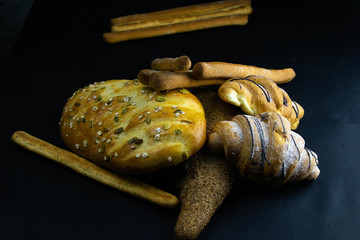 Different kinds of fresh bread with grain on black rustic background.