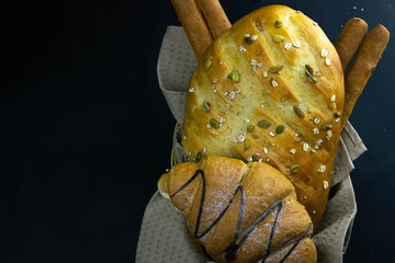 Different kinds of fresh bread with grain on black rustic background.
