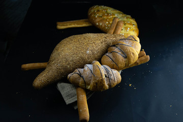Different kinds of fresh bread with grain on black rustic background.