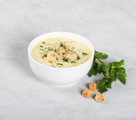 Cheese puree soup with chicken meatballs and dill and parsley in a bowl